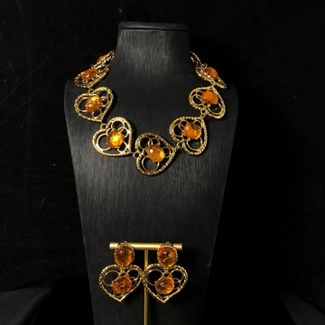 Vintage-style jewelry, including necklaces and earrings, featuring orange jelly resin inlays, a hollowed-out heart pendant design, and an elegant aesthetic