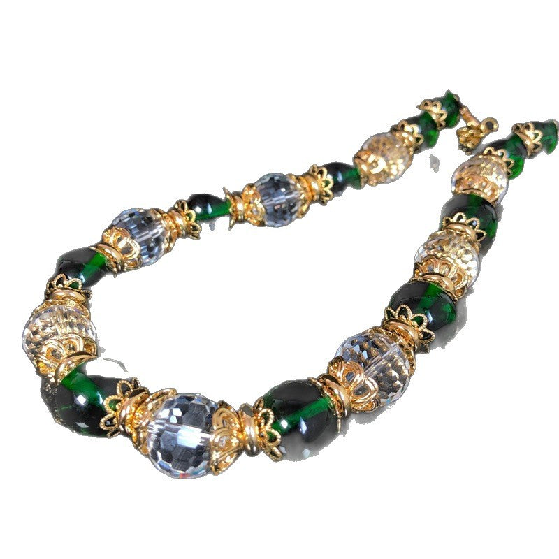 Stylish and elegant necklace and earrings featuring a design-forward, gold-plated finish, with delicate glass beads and faceted transparent glass beads