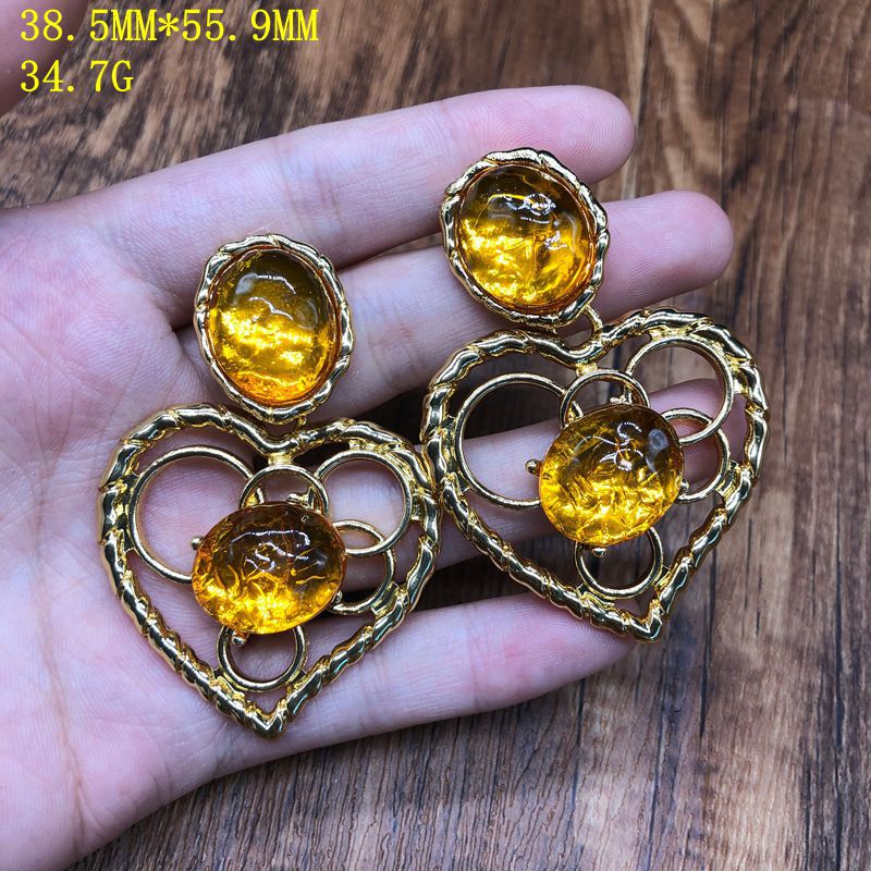 Vintage-style jewelry, including necklaces and earrings, featuring orange jelly resin inlays, a hollowed-out heart pendant design, and an elegant aesthetic