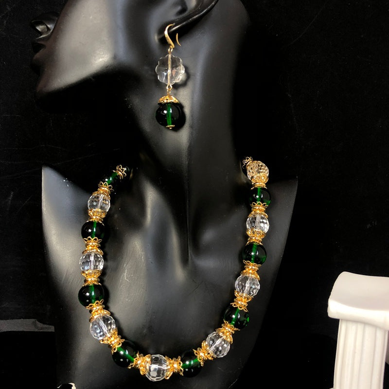 Stylish and elegant necklace and earrings featuring a design-forward, gold-plated finish, with delicate glass beads and faceted transparent glass beads