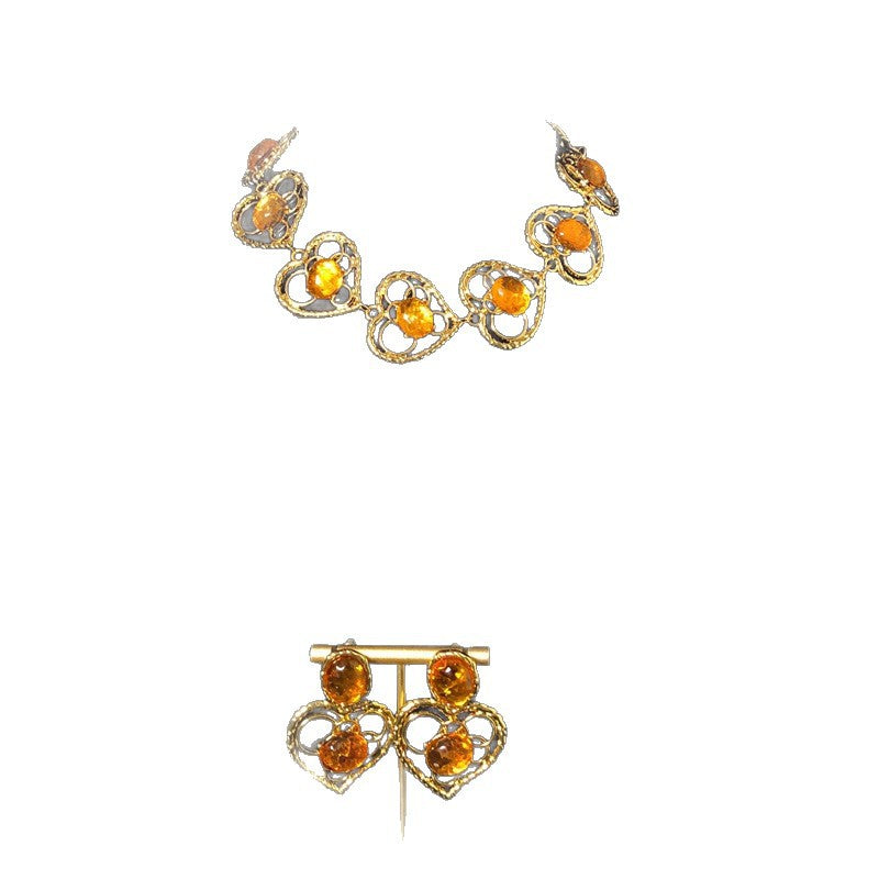Vintage-style jewelry, including necklaces and earrings, featuring orange jelly resin inlays, a hollowed-out heart pendant design, and an elegant aesthetic