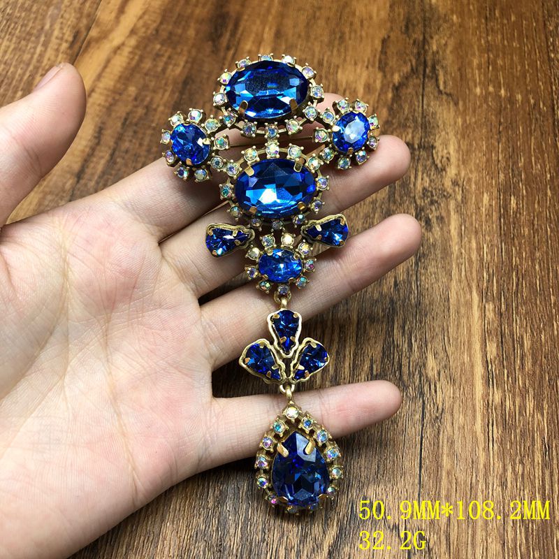 Vintage-style, exquisite, and luxurious brooch with diamond accents, featuring a classic design, a blue hue, and a sophisticated aesthetic, with copper settings and an aged finish