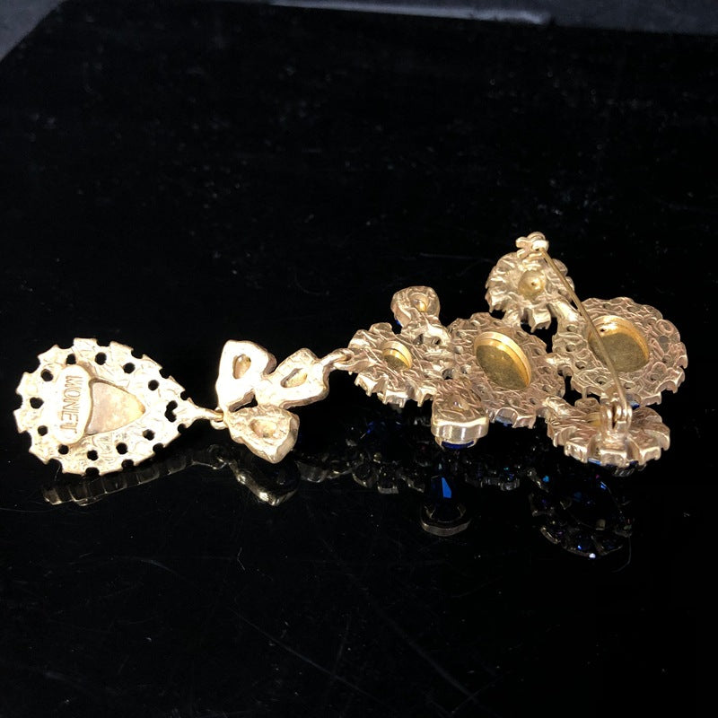 Vintage-style, exquisite, and luxurious brooch with diamond accents, featuring a classic design, a blue hue, and a sophisticated aesthetic, with copper settings and an aged finish