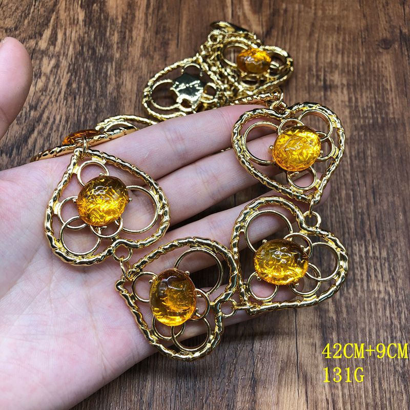 Vintage-style jewelry, including necklaces and earrings, featuring orange jelly resin inlays, a hollowed-out heart pendant design, and an elegant aesthetic